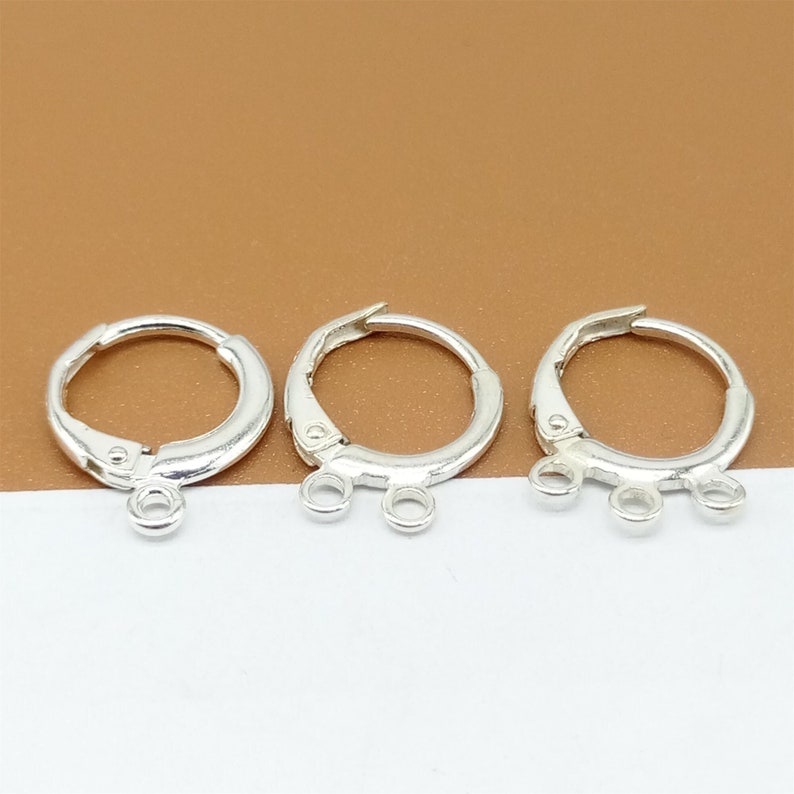 May include: Three silver earring hoops with three jump rings attached to each hoop.
