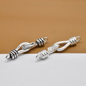 May include: Two silver-toned clasps with a twisted rope design. The clasps are made of metal and have a polished finish.