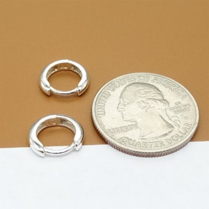 May include: Two silver hoop earrings, each about the size of a US quarter.