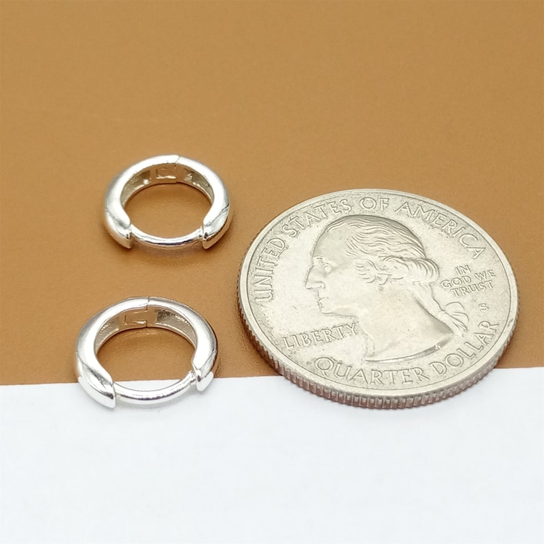 May include: Two silver hoop earrings, each about the size of a US quarter.