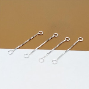 May include: Four silver chain extenders with jump rings at each end. The extenders are different lengths.