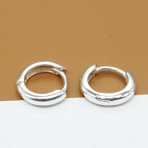 May include: A pair of silver hoop earrings. The earrings are simple and classic, with a smooth, polished finish.