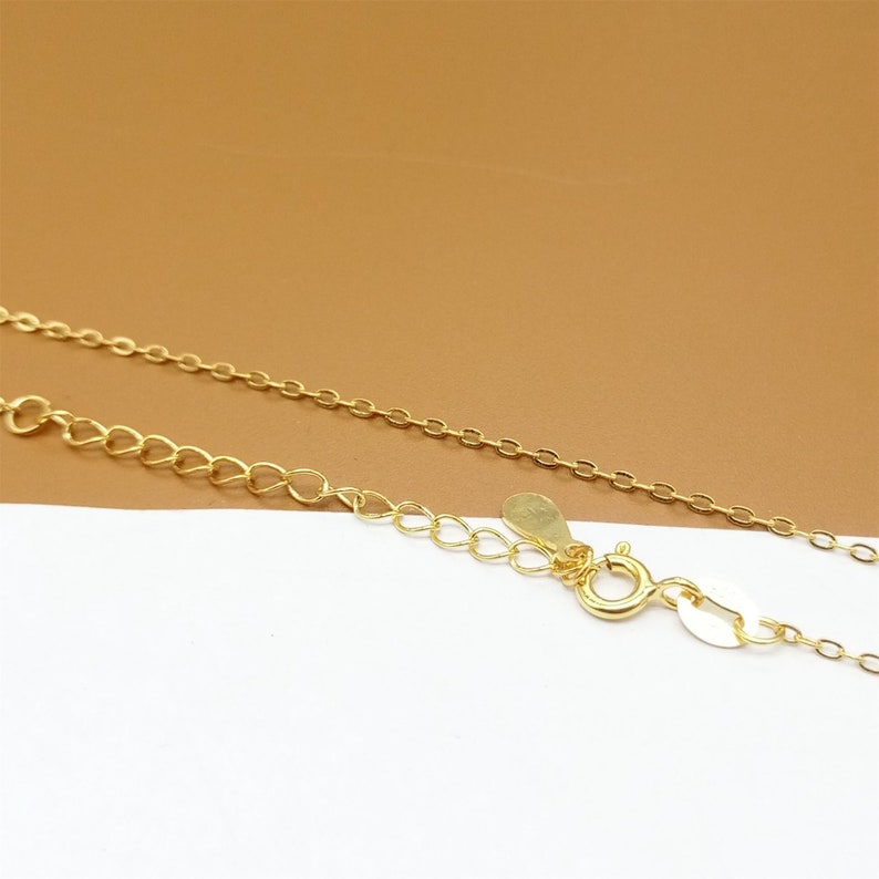 Op de afbeelding: Een gouden ketting met een kreeftensluiting. De ketting is gemaakt van kleine, met elkaar verbonden ovalen.