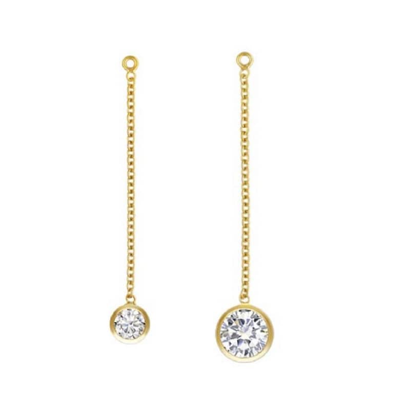 May include: A pair of gold dangle earrings with a single round clear stone at the end of each chain.
