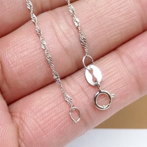 May include: A silver chain necklace with a lobster clasp fastening. The chain is a delicate, twisted design.