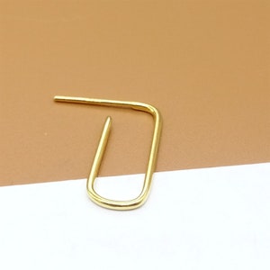 May include: A gold-colored, open hoop earring with a simple, minimalist design.