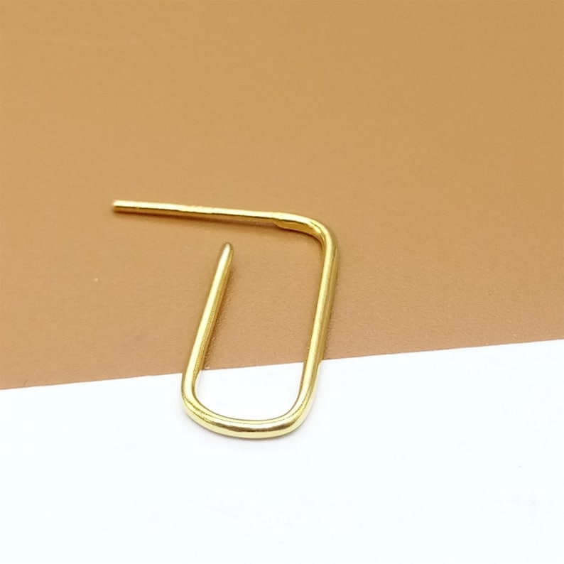 May include: A gold-colored, open hoop earring with a simple, minimalist design.