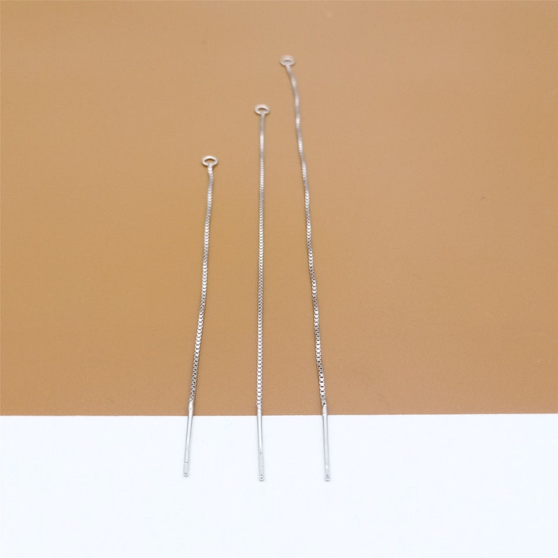 May include: Three silver chain extenders of varying lengths, each with a small loop at the top.