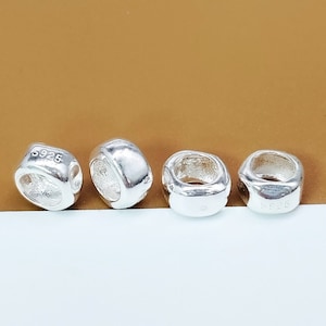 May include: Four silver-toned metal spacer beads with a round hole in the center. The beads are slightly rounded and have a smooth surface. The beads are marked with the number "S925" on the side.