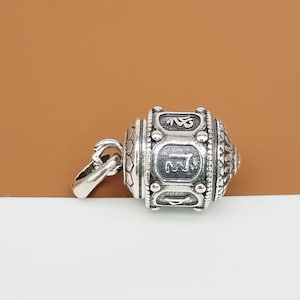 Puede incluir: Encanto de plata en forma de rueda de oraci&oacute;n con detalles intrincados y s&iacute;mbolos grabados. El encanto tiene un bucle para sujetarlo a un collar o pulsera.