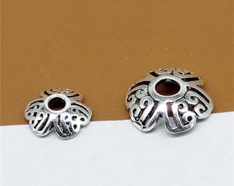 May include: Two silver metal bead caps with intricate floral designs. The caps have a round hole in the center for threading beads.