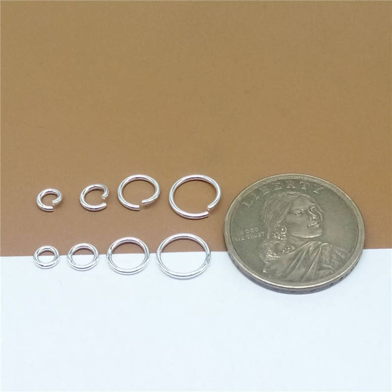 May include: A set of seven silver jump rings of varying sizes, next to a US quarter for scale.