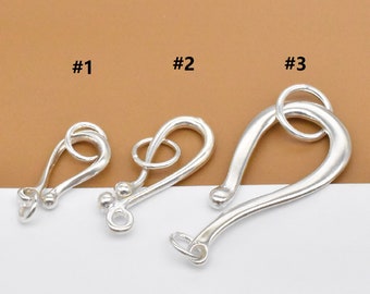 May include: Three silver-toned metal clasps, labeled #1, #2, and #3. The clasps are different shapes and sizes. #1 is a small, simple loop. #2 is a larger loop with a decorative twist. #3 is a large, curved hook.