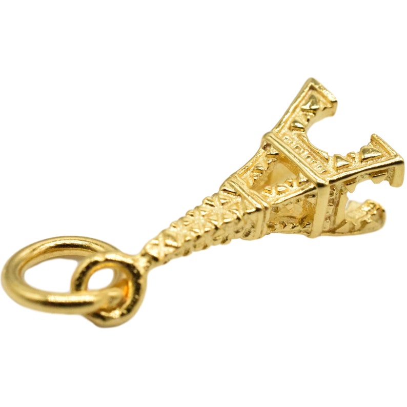 May include: Gold-toned Eiffel Tower charm with a loop for attaching to a necklace or bracelet.
