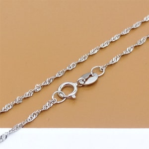 May include: A silver chain necklace with a lobster clasp fastening. The chain is a delicate, twisted rope design.