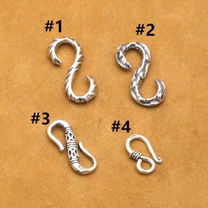 Könnte beinhalten: Vier silberfarbene Metallverschlüsse mit unterschiedlichen Designs. Die Verschlüsse sind von 1 bis 4 nummeriert.