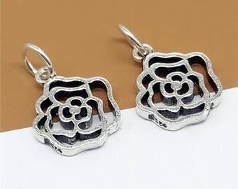 May include: Two silver rose charm pendants with an intricate openwork design. The charms have a loop at the top for attaching to a bracelet or necklace.