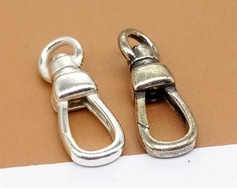 May include: Two metal swivel clasps, one silver and one brass, with a rounded oval shape. The clasps are designed for attaching to a chain or strap.