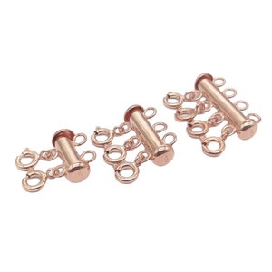 May include: Three gold-toned metal clasps for necklaces or bracelets. Each clasp has a cylindrical center piece with multiple loops on either side.