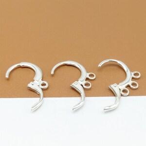 May include: Three silver earring hooks with three loops on each hook. The hooks are designed to be used for attaching earrings to a necklace or bracelet.