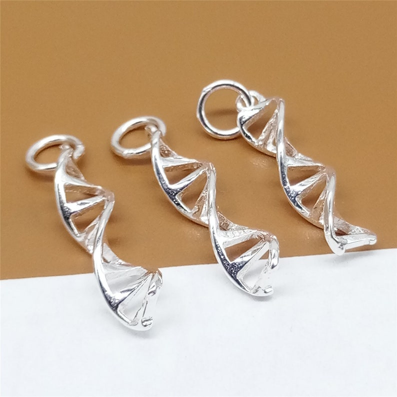 K&ouml;nnte beinhalten: Drei silberfarbene DNA-Doppelhelix-Anh&auml;nger. Jeder Anh&auml;nger hat eine &Ouml;se oben zum Anbringen an einer Kette oder einem Armband.