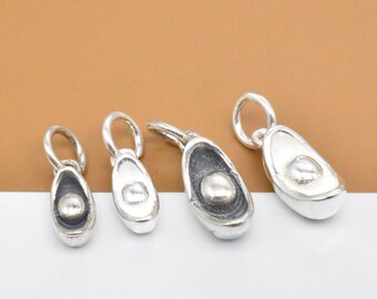 May include: Four silver avocado charm pendants of varying sizes. Each charm features a detailed avocado design with a pit in the center.