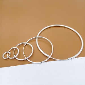 May include: Set of five silver hoop earrings of varying sizes. The hoops are all smooth and have a polished finish.