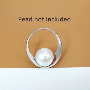Op de afbeelding: Zilveren hanger met een cirkelvormig ontwerp, met ruimte voor een parel. De tekst "Pearl not Included" is zichtbaar boven de hanger.