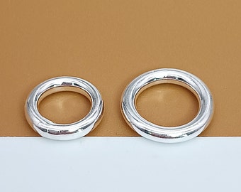 May include: Two silver rings, one larger than the other, on a brown background.