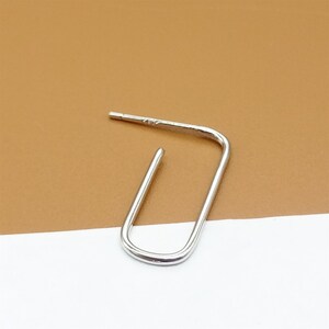 May include: A silver hoop earring with a simple, open, rectangular shape.