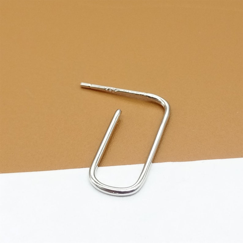 May include: A silver hoop earring with a simple, open, rectangular shape.