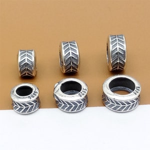 May include: Five silver spacer beads with an arrow design. The beads are different sizes and have the number "925" stamped on them.