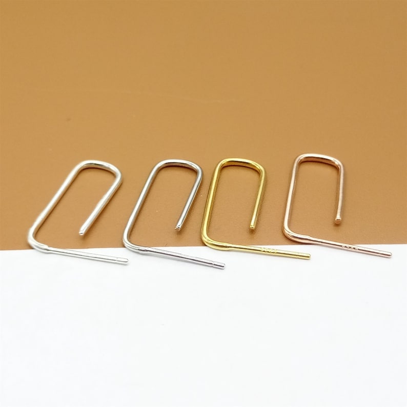 May include: Four pairs of minimalist earrings in silver, gold, and rose gold. Each earring is a simple, open loop shape.