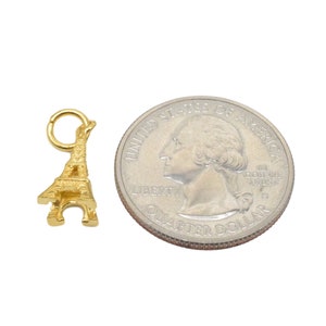 May include: Gold-colored Eiffel Tower charm pendant, approximately the size of a US quarter.