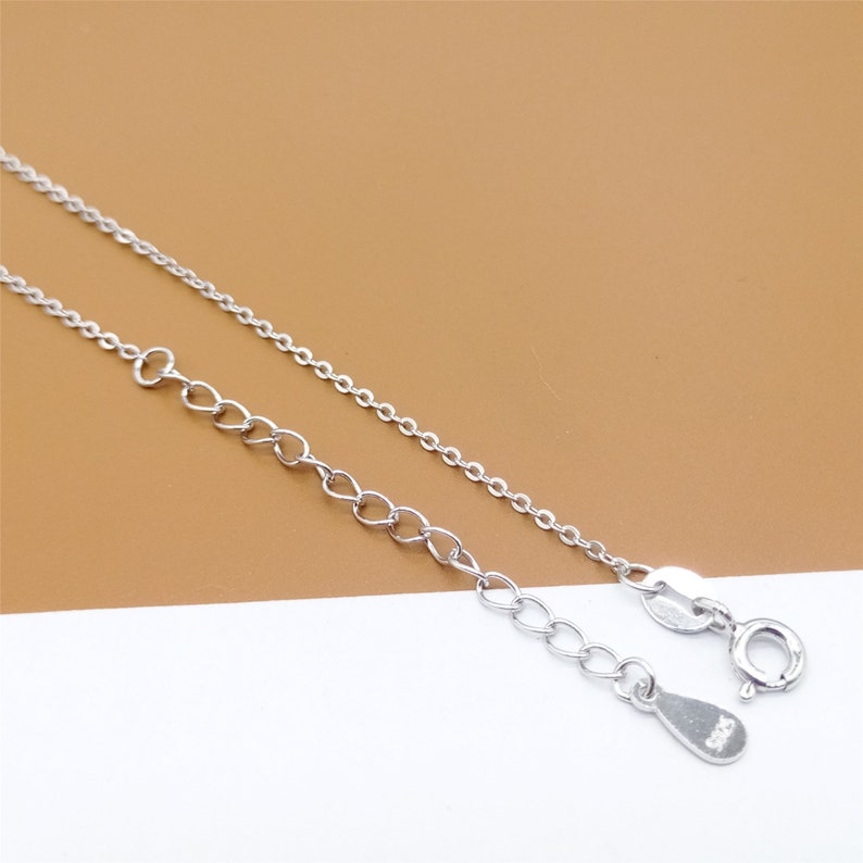 Op de afbeelding: Een zilveren ketting met een karabijn sluiting en een klein zilveren label met de tekst "925".