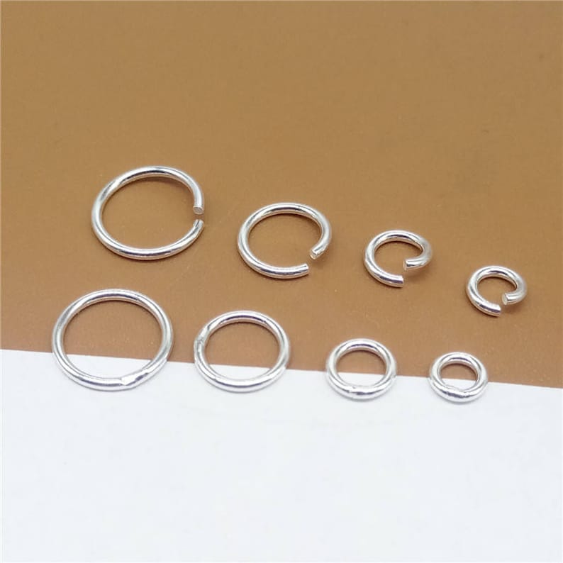 May include: A set of eight silver jump rings in various sizes. The jump rings are smooth and shiny.
