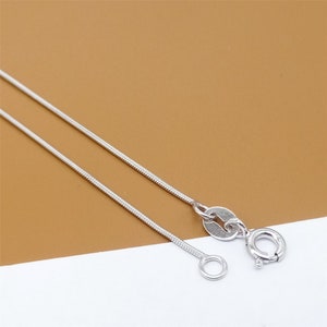 May include: A silver snake chain necklace with a lobster clasp closure.