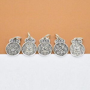 May include: Five silver charms with Chinese characters on a brown background. The characters are "金", "木", "水", "火", and "土".