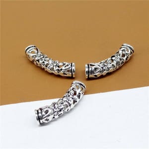 May include: Three silver-toned metal end caps with a floral design. The end caps are curved and have a hollow center.