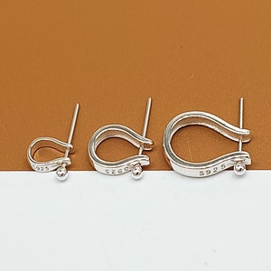 May include: Three silver hoop earrings with a curved design. The earrings are marked with "S925" on the back.