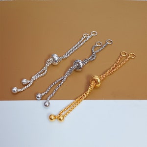 Könnte beinhalten: Drei verstellbare Armbänder aus Silber und Gold mit runden Perlen und einem verschiebbaren Knotenschluss.