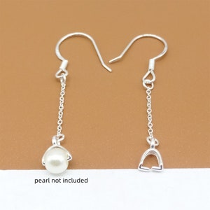 May include: A pair of silver earring findings with a chain and a loop at the bottom. The earring findings are designed to hold a pearl or other gemstone. "Pearl not included" is written below the earrings.