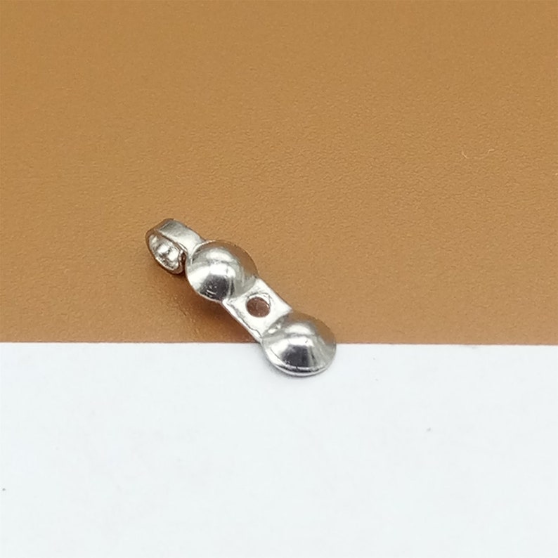 May include: Silver-toned metal jewelry finding with two round, domed ends and a loop at one end.