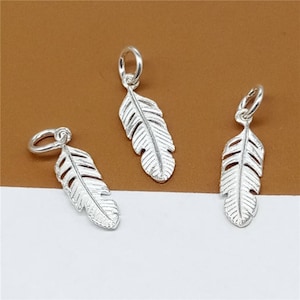 May include: Three silver feather charms with a loop at the top for attaching to jewellery. The feathers have a detailed, textured design.