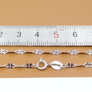 May include: A silver chain necklace with a delicate flower design. The chain is 5 mm wide and is measured against a ruler.