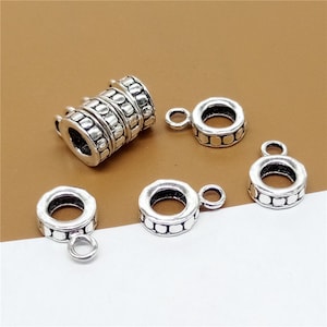 Puede incluir: Cinco tapones de cuentas de metal plateados con un diseño texturizado. Los tapones de cuentas tienen un pequeño bucle en el lateral para sujetarlos a las joyas.