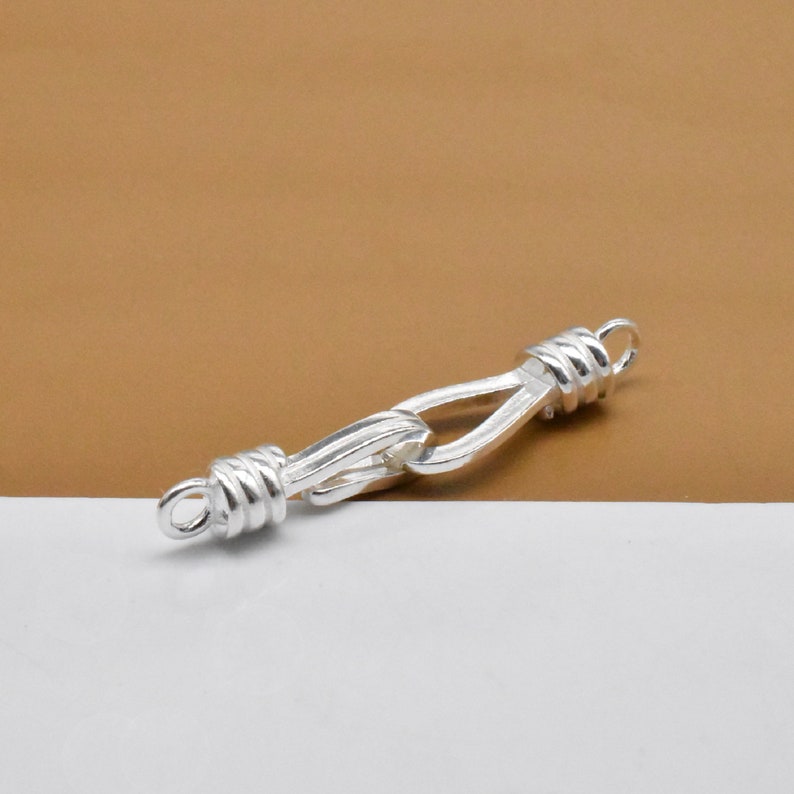 May include: Silver-toned metal clasp with a twisted rope design. The clasp is designed to connect two pieces of jewelry together.