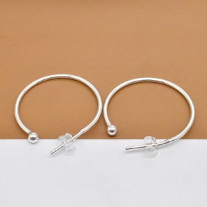 May include: A pair of silver hoop earrings with a small ball at the top of each hoop.