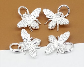 May include: Four silver bee charms with a loop for attaching to jewellery. The bees are detailed with wings, legs, and a textured body.