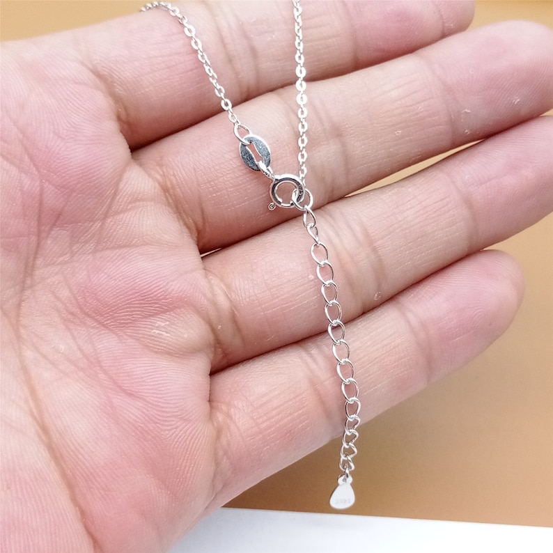 Op de afbeelding: Een zilveren ketting met een karabijn sluiting en een verstelbare lengte. De ketting is gemaakt van kleine, ronde schakels.